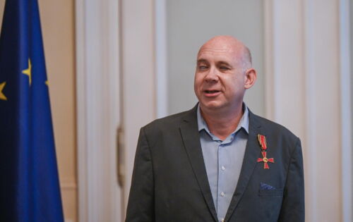 Karl Matthias Schäfer trägt ein graues Sakko, an dem das Bundesverdienstkreuz prangt. Er hat ein rundes Gesicht und einen kurzen grauen Haarkranz.