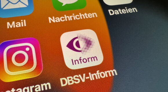 Auf einem Smartphone-Display sind verschiedene Apps zu sehen. In der Mitte die DBSV-Inform-App mit dem purpurnen Rasterauge auf weißem Grund.