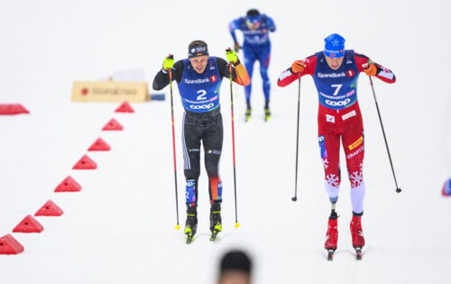 Para-Skilangläufer Sebastian Marburger fährt auf einer beschneiten Piste neben einem anderen Sportler. Beide tragen enge Skianzüge und stoßen mit den Skistöcken in den Schnee.
