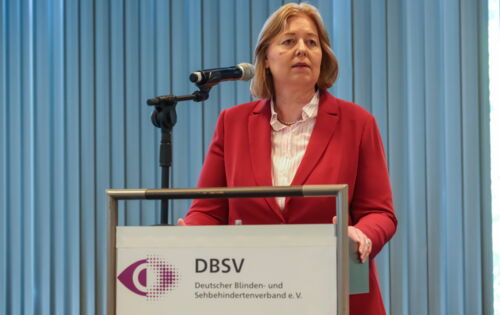 Bärbel Bas, Bundesministerin für Arbeit und Soziales, steht am Rednerpult und spricht in ein Mikrofon. Sie trägt einen roten Blazer über einem hellen Oberteil.