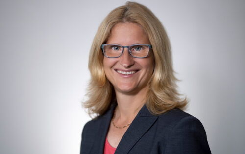 Christiane Möller blickt lächelnd in die Kamera. Sie hat schulterlanges blondes Haar und trägt eine Brille, einen dunklen Blazer und eine Kette.