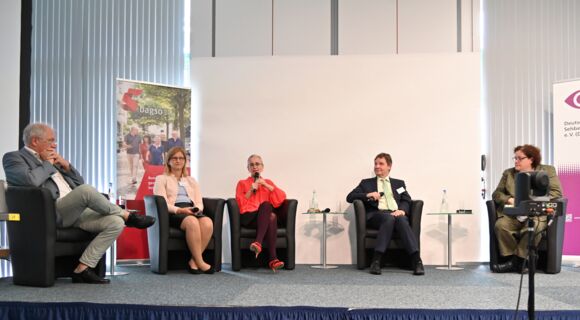 Podiumsdiskussion auf einer Bühne. In dunklen Sesseln sitzen von links nach rechts: Prof. Dr. Dr. Norbert Schrage, Christiane Möller, Prof. Dr. Kathleen Kunert (mit Mikrofon), Andreas Bethke und Dr. Sabine Lauber-Pohle.