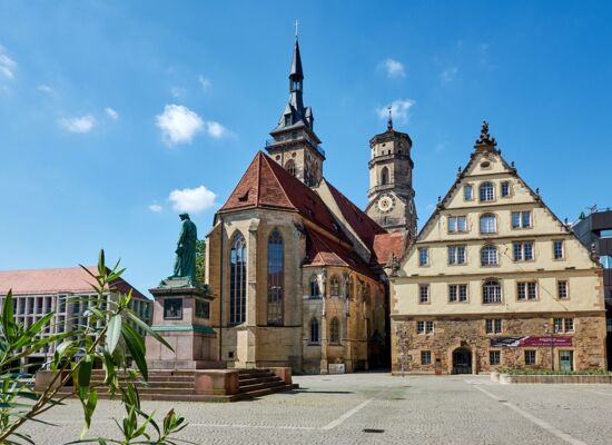 Der Stuttgarter Schillerplatz im gleißenden Sonnenschein: historische Gebäude und Statuen.