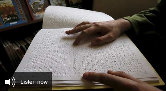 Screenshot der BBC-Webseite: Jemand liest mit den Händen ein Braille-Buch. In der linken unteren Ecke steht „Listen now“, englisch für „Jetzt anhören“.