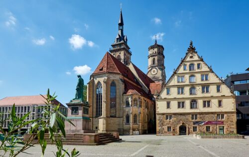 Der Stuttgarter Schillerplatz im gleißenden Sonnenschein: historische Gebäude und Statuen.