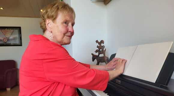 Klägerin Renate S., eine ältere Person im roten Oberteil mit Blumenohrring im Profil.