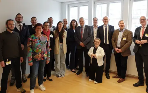 Die Gründungsmitgliedern der Initiative „Inklusive Katastrophenvorsorge Baden-Württemberg“ stehen nebeneinander in einem hellen Raum. Es sind 15 Personen. Eine von ihnen ist Simone Fischer, eine kleinwüchsige Frau mit blonden Haaren.