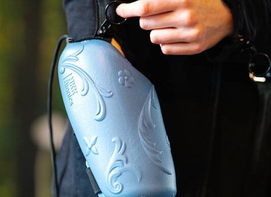 Myoelektrische Orthese eines Arms. Der Reißverschluss der Jacke, die die Person trägt, verläuft über den ganzen Ärmel.  Eine Hand öffnet ihn.