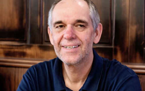 Kopf-Schulter-Portrait von Ottmar Miles-Paul: Er lächelt in die Kamera. Sein Haar ist grau, er hat eine hohe Stirn und dunkle Augenbrauen.