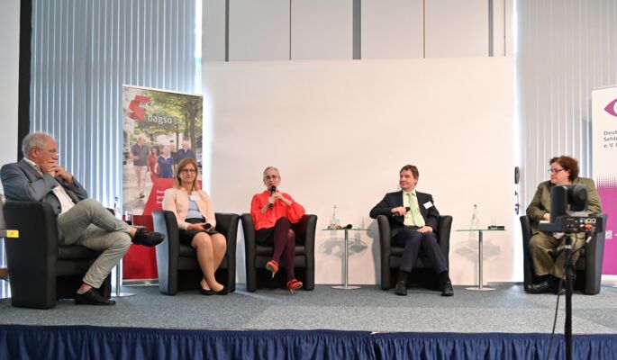 Podiumsdiskussion auf einer Bühne. In dunklen Sesseln sitzen von links nach rechts: Prof. Dr. Dr. Norbert Schrage, Christiane Möller, Prof. Dr. Kathleen Kunert (mit Mikrofon), Andreas Bethke und Dr. Sabine Lauber-Pohle.