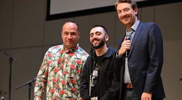 Die drei Comedians Khalil Khalil, Timur Turga und Jochen Prang stehen nebeneinander auf einer Bühne und lachen in die Kamera.