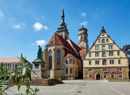 Der Stuttgarter Schillerplatz im gleißenden Sonnenschein: historische Gebäude und Statuen.