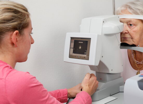 Voruntersuchung zur Kataraktoperation: eine Frau schaut einer älteren Frau mit einem Gerät in das Auge.