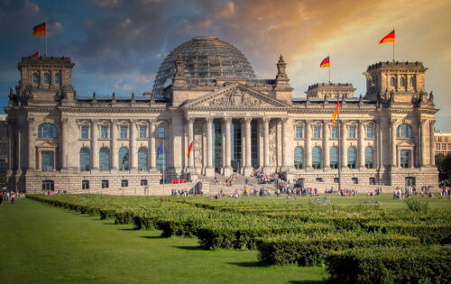 Das Reichstagsgebäude in Berlin mit seiner markanten Glaskuppel und wehenden deutschen Fahnen.