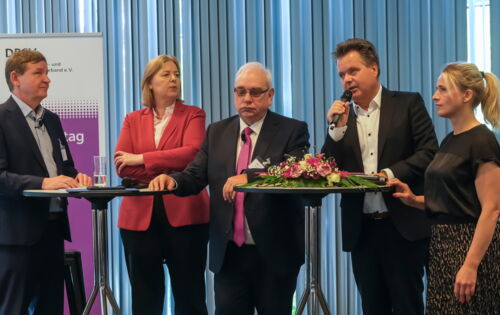 An zwei Stehtischen stehen nebeneinander (v. l. n. r.): Andreas Bethke, Bärbel Bas, Hans-Werner Lange, Jürgen Dusel und Verena Bentele. Dusel spricht in ein Mikro.