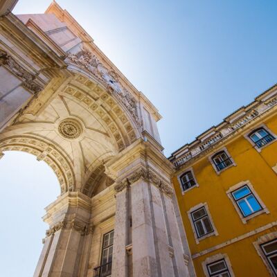 Ein Stadtbild von Lissabon. Ein hoher Torbogen erhebt sich über die Kamera.