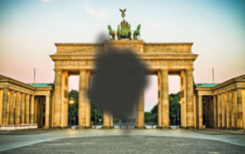 Ein leicht unscharfes Bild vom Brandenburger Tor, das in der Mitte eine schwarze, strahlenförmige Unschärfe hat, die Teile des Tors verdeckt.