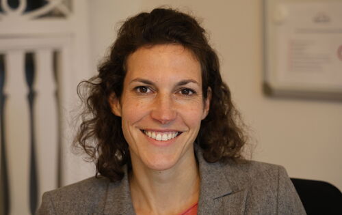 Jana Stasch-Bouws sieht strahlend in die Kamera. Sie hat ein schmales Gesicht, längeres lockiges dunkles Haar und große dunkle Augen.