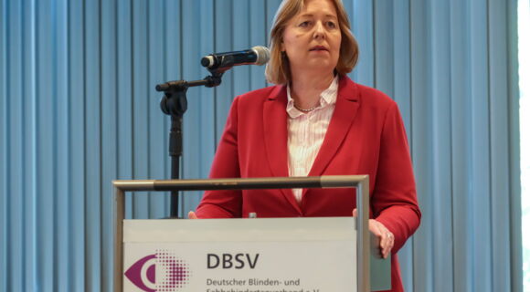 Bärbel Bas, Bundesministerin für Arbeit und Soziales, steht am Rednerpult und spricht in ein Mikrofon. Sie trägt einen roten Blazer über einem hellen Oberteil.