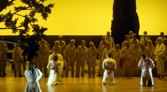 AudioSzene aus der „Zauberflöte“ an der Deutschen Oper Berlin: Viele Menschen sind zu sehen, im Vordergrund knien vier Gefangene.