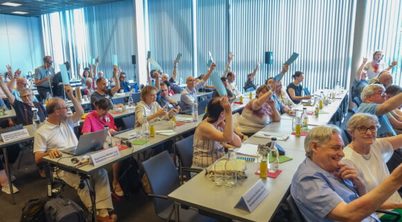 An langen Tischreihen sitzen die Delegierten des DBSV-Verbandstags. Vereinzelt halten sie Wahlkarten hoch.