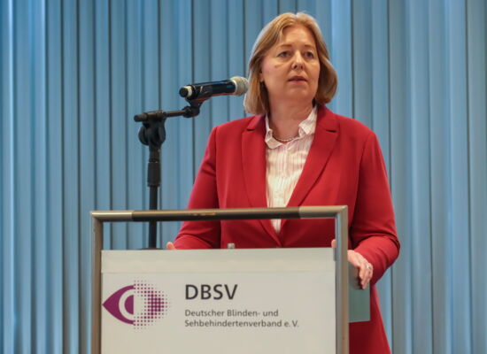 Bärbel Bas, Bundesministerin für Arbeit und Soziales, steht am Rednerpult und spricht in ein Mikrofon. Sie trägt einen roten Blazer über einem hellen Oberteil.