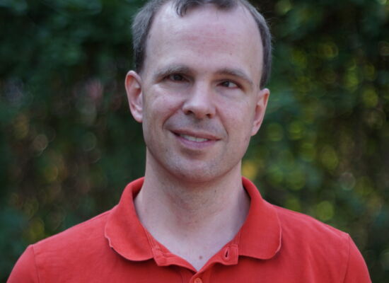 Alexander Pfingstl lächelt in die Kamera. Er hat kurzes, an den Seiten dichteres Haar und trägt ein Shirt mit kurzem Kragen.