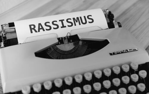 Eine Schreibmaschine mit einem angefangenen Blatt. In Großbuchstaben steht Rassismus dort geschrieben.