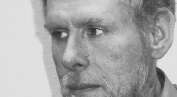 Porträt von Thomas Drerup in schwarz-weiß. Der weiße Mann mit hellen Haaren und Bart schaut ernst nach links zur Seite.