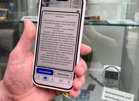 Eine linke Hand richtet ein Smartphone auf ein Schaufenster. Auf dem Display ist viel Text zu erkennen
