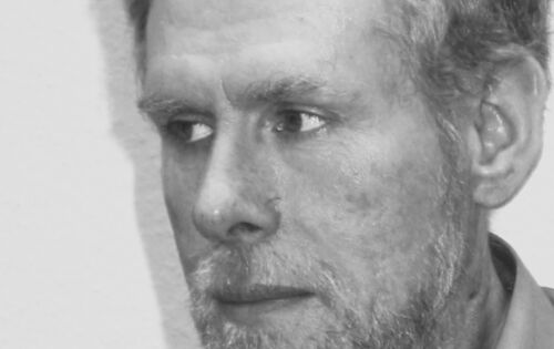 Porträt von Thomas Drerup in schwarz-weiß. Der weiße Mann mit hellen Haaren und Bart schaut ernst nach links zur Seite.