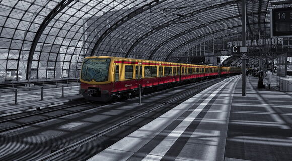 Ein menschenleerer Bahnsteig mit weißem Leitstreifen, eingefasst von zwei dunklen Kontraststreifen.