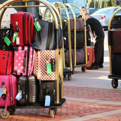 Ein altmodischer Gepäckwagen, auf dem sich Gepäckstücke aller Art und Farbe stapeln.