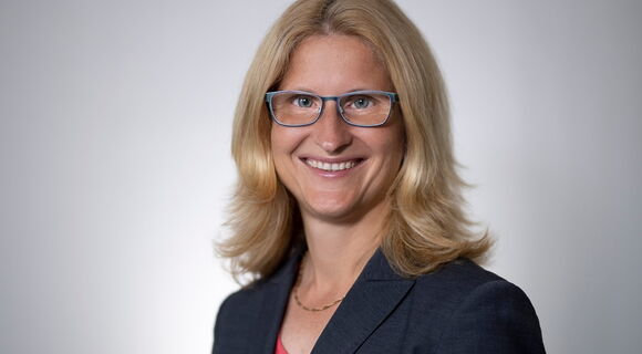 Christiane Möller blickt lächelnd in die Kamera. Sie hat schulterlanges blondes Haar und trägt eine Brille, einen dunklen Blazer und eine Kette.