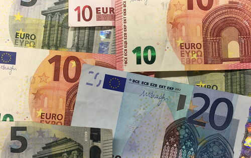 Mehrere Euro-Banknoten in verschiedenen Werten (5, 10, 20) liegen überlappend aufeinander. Die Scheine zeigen unterschiedliche Farben und Architektur-Motive, die typisch für Euro-Noten sind.