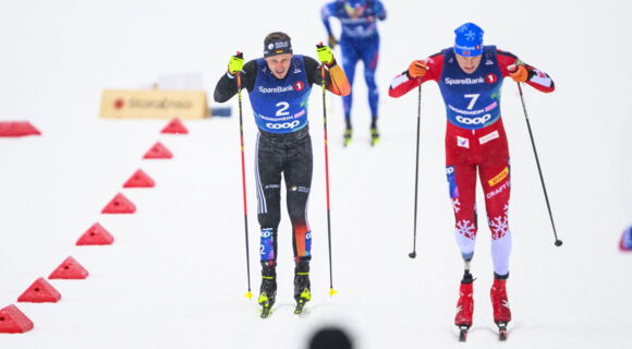 Para-Skilangläufer Sebastian Marburger fährt auf einer beschneiten Piste neben einem anderen Sportler. Beide tragen enge Skianzüge und stoßen mit den Skistöcken in den Schnee.