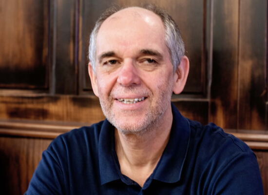 Kopf-Schulter-Portrait von Ottmar Miles-Paul: Er lächelt in die Kamera. Sein Haar ist grau, er hat eine hohe Stirn und dunkle Augenbrauen.