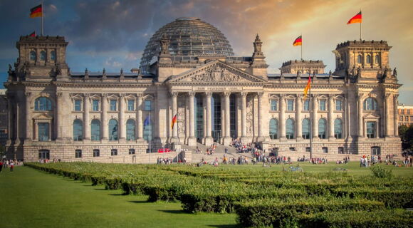 Das Reichstagsgebäude in Berlin mit seiner markanten Glaskuppel und wehenden deutschen Fahnen.