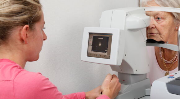 Voruntersuchung zur Kataraktoperation: eine Frau schaut einer älteren Frau mit einem Gerät in das Auge.