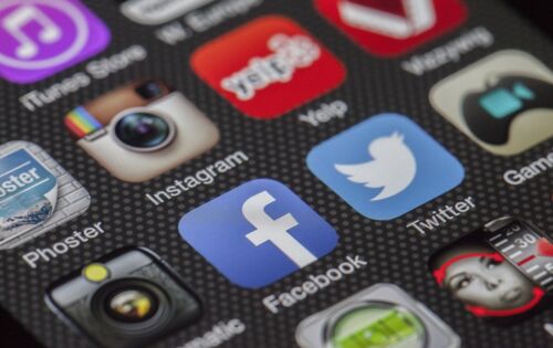 Der Bildschirm eines Smartphones zeigt mehrere Reihen von Symbolen für Social-Media-Plattformen, darunter Facebook, YouTube und Instagram.