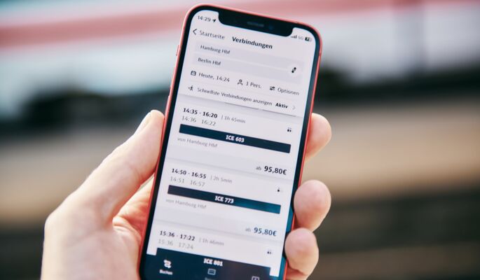 Auf einem Smartphone-Display ist die App "DB-Navigator" geöffnet. Es werden Verbindungen von Hamburg nach Berlin angezeigt.