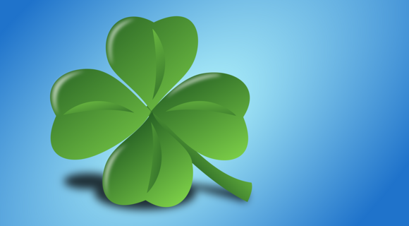 Ein grünes, vierblättriges Kleeblatt vor einem sanft verwaschenen blauen Hintergrund.