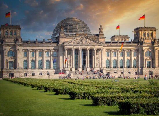 Das Reichstagsgebäude in Berlin mit seiner markanten Glaskuppel und wehenden deutschen Fahnen.