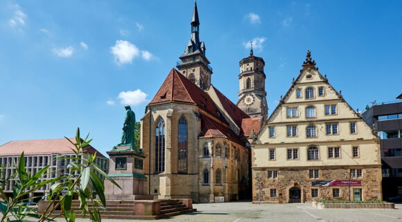 Der Stuttgarter Schillerplatz im gleißenden Sonnenschein: historische Gebäude und Statuen.