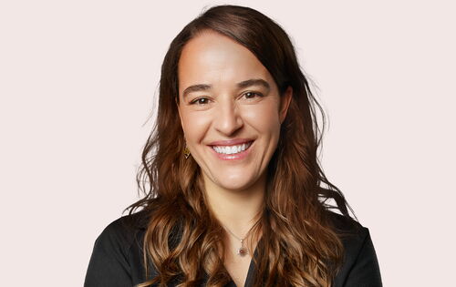 Heike Heubach lächelt. Sie hat langes, dunkles Haar, das sie nach links gescheitelt trägt.