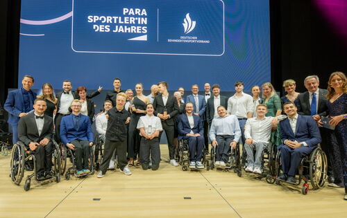 Gruppenbild mit den Para-Sportlerinnen und -Sportlern des Jahres 2024. Sie stehen und sitzen in mehreren Reihen vor einer großen Leinwand mit Veranstaltungslogo.