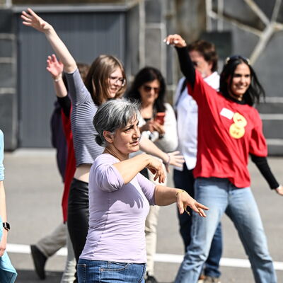 Mehrere Frauen, zum Teil mit Sonnenbrillen, bewegen sich beim Zumba-Workout auf dem Berliner Platz. Viele recken den rechten Arm in die Luft.
