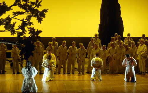 AudioSzene aus der „Zauberflöte“ an der Deutschen Oper Berlin: Viele Menschen sind zu sehen, im Vordergrund knien vier Gefangene.