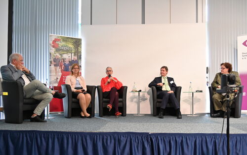 Podiumsdiskussion auf einer Bühne. In dunklen Sesseln sitzen von links nach rechts: Prof. Dr. Dr. Norbert Schrage, Christiane Möller, Prof. Dr. Kathleen Kunert (mit Mikrofon), Andreas Bethke und Dr. Sabine Lauber-Pohle.