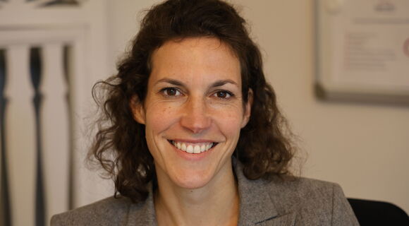 Jana Stasch-Bouws sieht strahlend in die Kamera. Sie hat ein schmales Gesicht, längeres lockiges dunkles Haar und große dunkle Augen.
